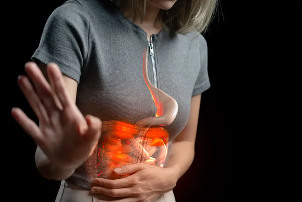 Una mujer se toca el abdomen con gesto de dolor por la acidez de estómago